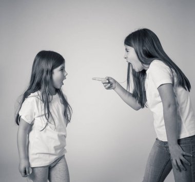 Bir tartışma olan etkileşim kardeş portresi. Ablası bağırıyor ve kızgın üzgün küçük kız kardeşine öfkeli jestler yapıyor. Kardeşler kötü ilişki ve çocuk çakışmaları.