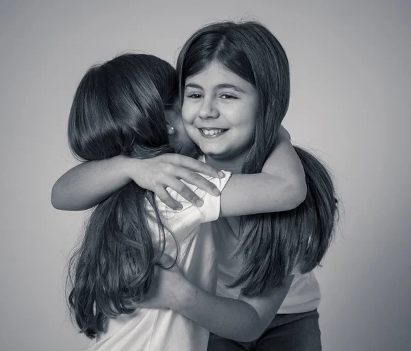 Portrait of two pretty loving sisters hugging each other in happy moments together and older and younger sister relationship. Children friendship and family concept.