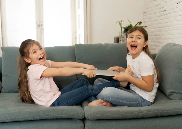 Younger and older girls fighting for laptop arguing over playing on the internet. Lifestyle portrait of sisters not sharing computer in Relationship between siblings and technology addiction concept.