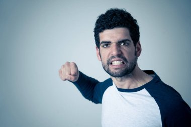 Genç hipster erkek portresi öfkeli hoşnutsuz ve rahatsız yüz ifadesi ile öfkeli görünümlü. Nötr arka planda izole edilmiş. İnsanlarda ve olumsuz duygu veya duygu tepkisi.