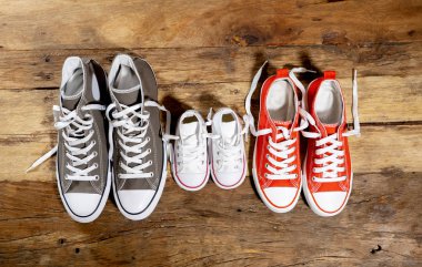 Lastikbotlar spor ayakkabı ayakkabı baba anne ve oğlu kızı ailesinin tatlı ev beraberlik mutlu aile ebeveynlik ve yaşam tarzı kavramı farklı boyutlarda vintage ahşap zemin üzerinde kavramsal görüntü.