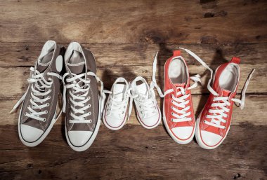 Lastikbotlar spor ayakkabı ayakkabı baba anne ve oğlu kızı ailesinin tatlı ev beraberlik mutlu aile ebeveynlik ve yaşam tarzı kavramı farklı boyutlarda vintage ahşap zemin üzerinde kavramsal görüntü.