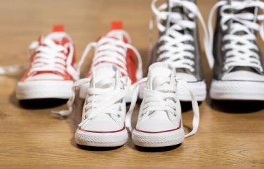 Lastikbotlar spor ayakkabı ayakkabı baba anne ve oğlu kızı aile tatlı ev beraberlik mutlu aile ebeveynlik farklı boyutlarda ahşap zemin üzerinde ve bir bebek kavram bekliyor kavramsal görüntü.