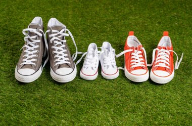 Kavramsal görüntü aile baba anne ve oğlu kız mutlu anları birlikte ebeveynlik aile eğitim ve yaşam tarzı kavram adam kadın ve çocuk boyutlarda yeşil çimenlerin üzerinde spor ayakkabı lastikbotlar.