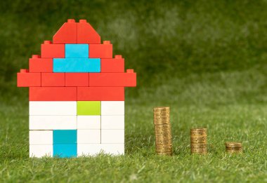 Kavramsal görüntü oyuncak evi ve yeşil çim alan üst sikkelerinde yığınları görüntülemek ve uzay Emlak Yatırım kaydetme ve ev ipotek satın alma gayrimenkul içinde kopyalama ve sigorta ve kavram banka kredisi.