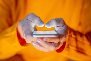 Online oynarken ve metin renkli bir arka plan ile akıllı telefon üzerinden ekran telefon bağımlılığı Internet oyun bağlantısı ve yeni teknoloji ışık göndererek genç veya yetişkin kadın kapatmak.