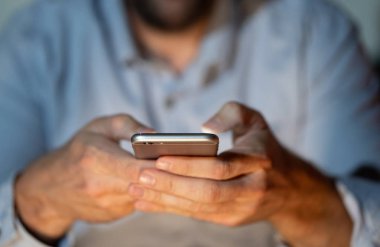 Online oynarken ve metin renkli bir arka plan ile akıllı telefon üzerinden ekran telefon bağımlılığı Internet oyun bağlantısı ve yeni teknoloji ışık göndererek genç veya yetişkin insanın yakın çekim.