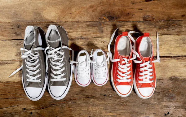 Conceptual image of gumshoes sneakers shoes of father mother and son daughter family on vintage wood floor in different sizes in Sweet home togetherness Happy Family Parenting and lifestyle concept.