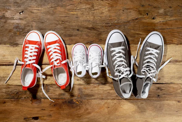 Conceptual image of gumshoes sneakers shoes of father mother and son daughter family on vintage wood floor in different sizes in Sweet home togetherness Happy Family Parenting and lifestyle concept.