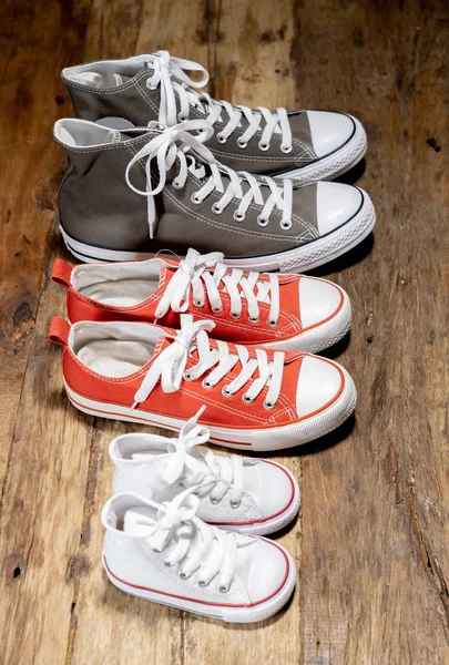 Conceptual image of gumshoes sneakers shoes of father mother and son daughter family on vintage wood floor in different sizes in Sweet home togetherness Happy Family Parenting and lifestyle concept.