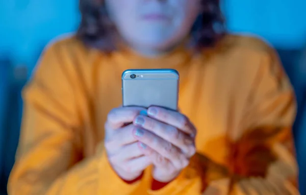 Close up of teenager or adult woman playing online and sending text on smart phone with a colorful background light from the screen in Mobile addiction Internet gaming Connections and New technology.