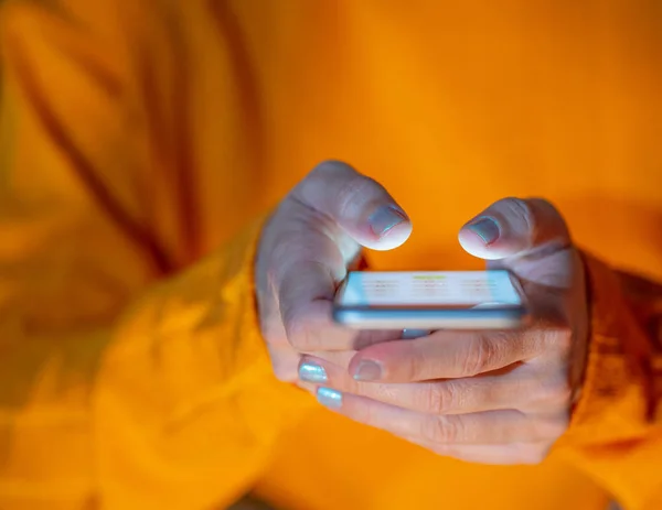 Hands of young woman or teenager sending text on social media app in Internet and Mobile addiction Cyberbullying Communications and Modern technology concept in colorful background and screen light.