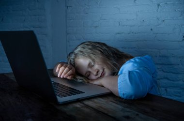 Sevimli kız öğrenci çocuk oynarken ve gece geç saatlerde online sörf. Çocuk internet oyunları ve sosyal medya cant uyku bağımlısı dizüstü bağımlısı. çocukluk ve internet bağımlılığı.