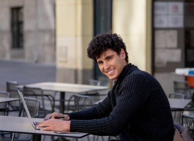 Yakışıklı genç adam bir Avrupa şehir kahve dükkanında teras dışında dizüstü bilgisayar üzerinde çalışıyor. Öğrenci Duygu mutlu ve memnun. Avrupa'da online eğitim ve teknoloji konsepti nde seyahat.