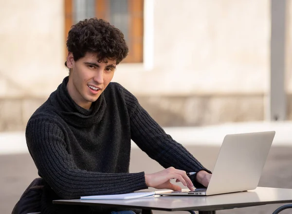 ヨーロッパの都市のコーヒーショップのテラスの外でラップトップコンピュータで働くハンサムな若者 学生は幸せと満足感を感じています ヨーロッパを旅するオンライン教育と技術コンセプト — ストック写真