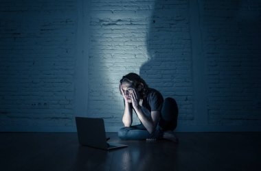 Ciddi dizüstü bilgisayar ile perişan genç genç adam siber zorbalık ve taciz acı online veya dedikodu duygu umutsuz ve siber zorbalık ve sosyal medya aşağılanmış duygu tarafından istismar ediliyor.