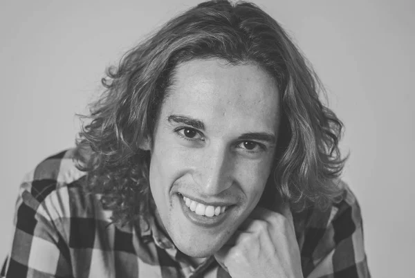 Black and white portrait of carefree male in casual t-shirt looking confident and self-assured. Smiling and staring at camera. Studio shot. In natural beauty, people modeling and lifestyle concept.