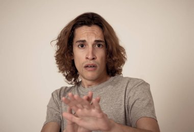 Genç adam korkmuş ve korku ve anksiyete korkmuş jestler yaparak şok hissi. Dehşete düşmüş çaresiz bir genç kendini saldırganlıktan korumaya çalışıyor. Halk ifadeleri ve gençlik şiddeti.