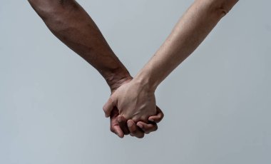 Multiracial couple holding hands together in love. White and black skin arms holding together. Conceptual image of world unity interracial love and understanding in tolerance and diversity. clipart