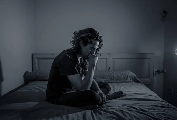 Devastated millennial man crying sad feeling hurt and hopeless suffering Depression. Depressed teenager victim of bullying or abuse sitting on bed alone in despair at night. In teenage Mental health.