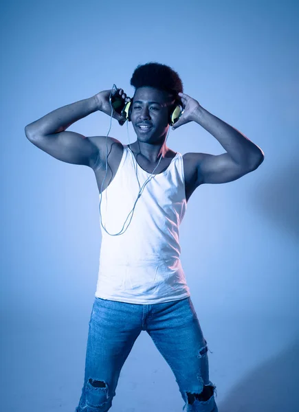 強いアフリカ系アメリカ人の若いダンサーの男性は 音楽のオンラインダンスを聴き ヘッドフォンで歌います インターネットミュージックとテクノロジーコンセプトのディスコダンスフロアネオンライトを持つ芸術的な肖像画 — ストック写真