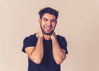 Pozitif insan yüz ifadeleri ve duygular. Mutlu yüz gülümseyen ve kamera neşeli jestleri ile onun 20s yakışıklı genç erkek portre. Yakın çekim nötr arka planda yalıtılmış.