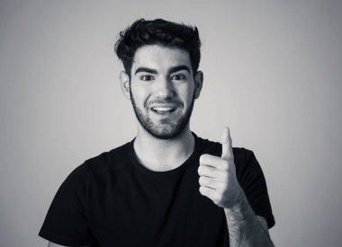İyi görünümlü genç adamın portresi, neşeli, mutlu ve memnun duygu başparmak kadar gösterir. Genç mutlu öğrenci erkek beyaz arka planda izole neşeli onay jest kadar başparmak yapma.