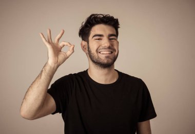 Genç latin adam gülümseyen ve Ok işareti yapıyor yakın portre. Kendinden emin ve tatmin olmuş hissediyorum. Nötr arka planda izole edilmiş. İnsanlar, olumlu insan yüz ifadeleri ve duygular kavramı.