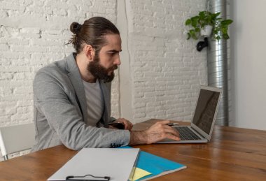 Hipster girişimci yaşam tarzı portre modern ev stüdyo ofisinde çalışan insanlar başlangıç ve küçük işletme. Mutlu genç freelancer bilgisayar üzerinde çalışan ve cep telefonu iş konuşurken.