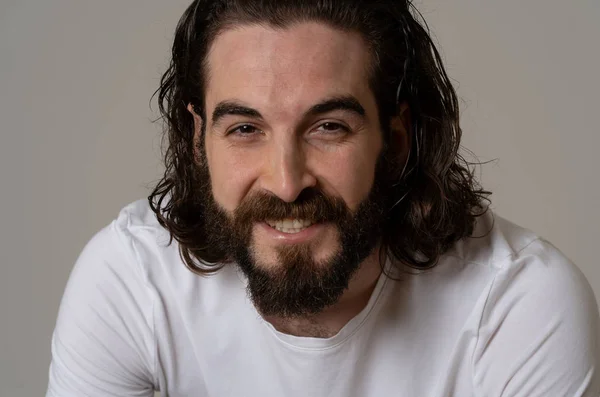 Portrait of attractive young model man with happy face, beautiful smile and long hair. Handsome hipster bearded man in his 20s. Studio shot. In People fashion and human facial expressions concept.