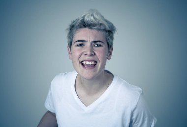 Kızgın yüzü ile genç çekici transseksüel genç adam Portresi. Kızgın ve öfkeli görünüyorsun. Yüz ifadeleri ve duygular. Nötr arka planda yalıtılmış.