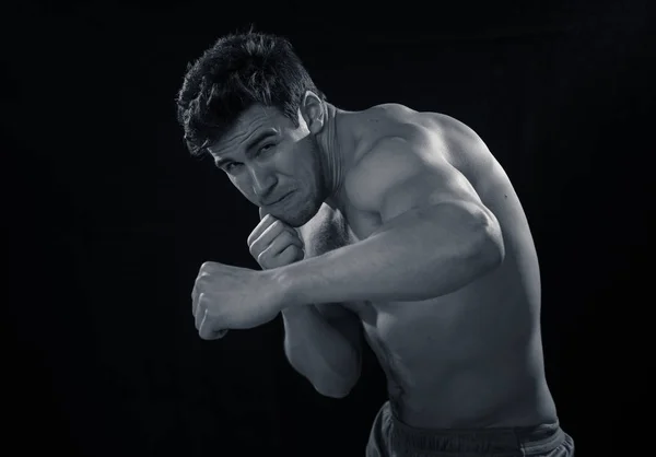 強さとモチベーション 黒い背景に隔離された戦闘ボクシングトレーニングジムトレーニングで強力なパンチを投げる強力なフィットネスマン スポーツ関連広告に優しい画像 — ストック写真