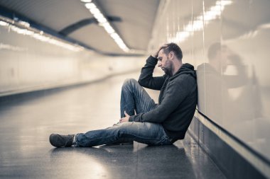 Üzgün genç adam ağlayan acı depresyon stres zemin sokak Metro'ya eğilerek duvar ruhsal bozukluk duygusal ağrı bağımlılığı yalnız ve işsizlik kavramı üzerinde umutsuz seyir üzerinde oturan.
