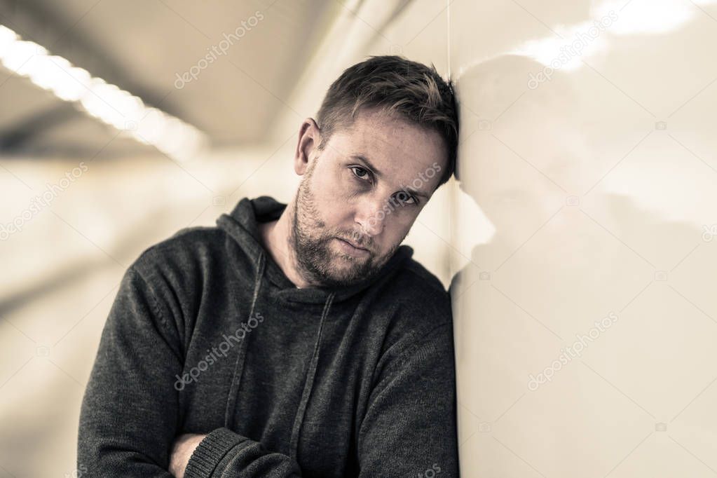 Sad jobless young man crying suffering depression stress sitting on ground street subway tunnel looking desperate leaning on wall alone in Mental disorder Emotional pain Drug abuse and Alcoholism.