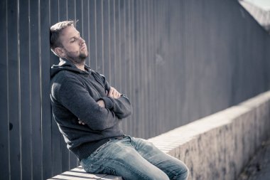 Genç çekici adam acı depresyon stres tek başına oturmak ve üzücü duygu endişeli ve işsizlik ruh sağlığı uyuşturucu ve alkol bağımlılığı kavram yalnız sokakta.