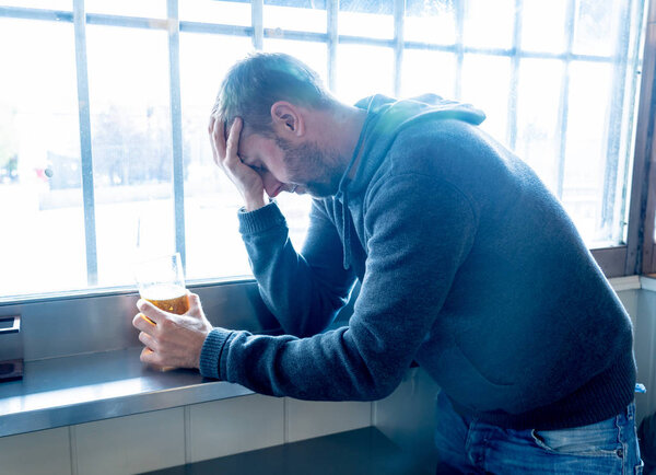 Portrait of a attractive caucasian man drinking beer in a bar pub feeling depressed unhappy and lonely in Alcohol Use Abuse Depression and mental health concept.