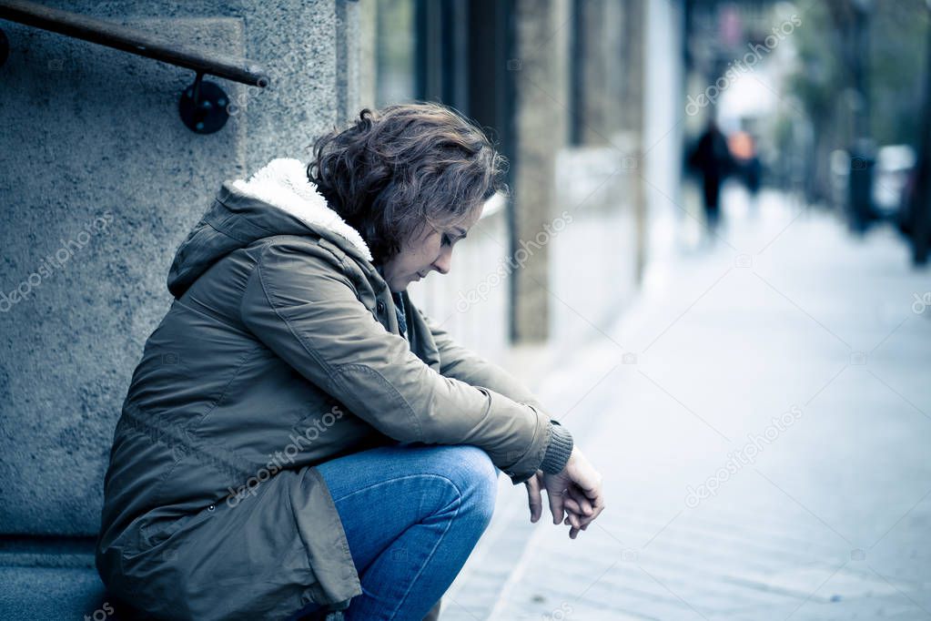 Attractive woman suffering from depression felling sad unhappy heartbroken and lonely sitting in city urban street in Mental health Emotional pain Abusive relationships and loneliness concept.