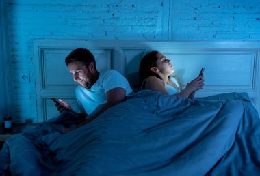 Teknoloji bağımlılığı birbirlerine ilgisizlik ve ilişki sorunları ve mobil internet bağımlılığı karanlıkta gece geç saatlerde akıllı telefonlarını kullanarak yatakta yatan öfke görmezden tarafından etkilenen çift.