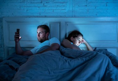Teknoloji bağımlılığı birbirlerine ilgisizlik ve ilişki sorunları ve mobil internet bağımlılığı karanlıkta gece geç saatlerde akıllı telefonlarını kullanarak yatakta yatan öfke görmezden tarafından etkilenen çift.