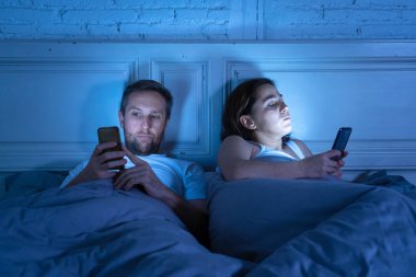 Teknoloji bağımlılığı birbirlerine ilgisizlik ve ilişki sorunları ve mobil internet bağımlılığı karanlıkta gece geç saatlerde akıllı telefonlarını kullanarak yatakta yatan öfke görmezden tarafından etkilenen çift.