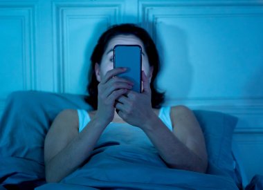 Sohbet ve akıllı telefonunu uykulu kullanarak internette sörf Internet bağımlısı genç güzel kadın sıkılmış ve mobil bağımlılığı ve uykusuzluk kavramı geceleri yorgun