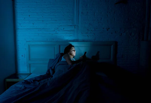 年轻迷人的妇女在深夜醒来使用智能手机躺在床上 在一个黑暗的卧室 使用移动聊天和发送信息在网络成瘾 移动滥用和失眠的概念 — 图库照片