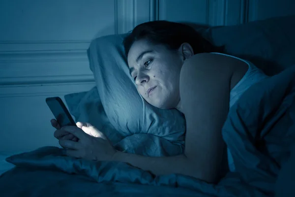チャットと眠そうな彼女のスマート フォンを使用してインターネット上でサーフィン中毒の若い美しい女性が退屈してインターネット 携帯依存症 不眠症概念で夜遅く疲れ — ストック写真
