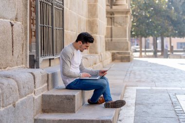 Dizüstü bilgisayar bloglama üzerinde çalışma, online sohbet ve e-posta bir Avrupa şehri açık havada kontrol trendy delikanlı. Öğrenci yaşam tarzı, teknoloji, eğitim ve uzak çalışma kavramı.