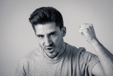Close up portrait of young violent man with angry face looking furious and crazy showing fits and pointing finger at the camera. Human facial expressions, emotions and behavioral problems concept. clipart