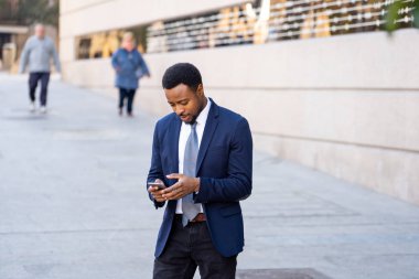 Genç adam akıllı aşınmaya üstünde hareket eden telefon açık havada city adlı metin e-posta ya da sosyal medya app sokak gönderme. Mutlu iş adamları, girişimci ve iş özgürlük iletişim teknoloji dışında çalışma.