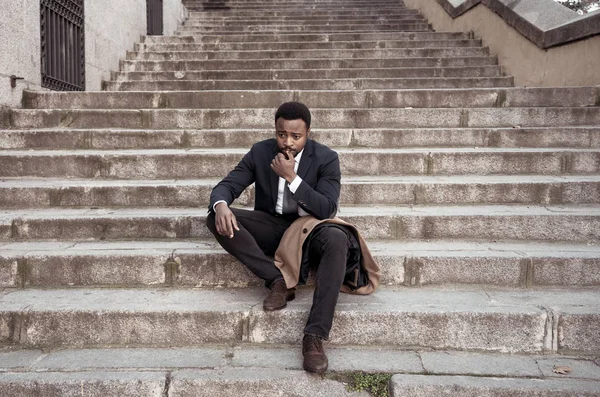 Young fired african american business man lost in depression crying sitting on ground street stairs suffering emotional pain sadness in grunge lighting. Unemployment, Depression and people concept.