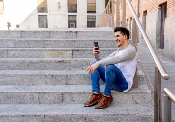 若い魅力的な大学キャンパスや街の階段のスマートな携帯電話で友人とのおしゃべりと話して幸せな 代の男 通信技術のインターネットとヨーロッパのまわりの旅行 — ストック写真