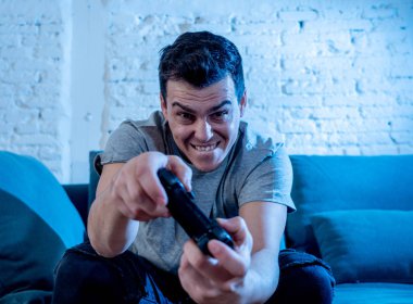 Genç öğrenci adam harcama zaman ucube yoğun mutlu yüz erkek oyun bağımlılığı konsol oyun İstasyonu ve video having oyunculuk ile kablosuz uzaktan joystick kullanarak video oyunları oynarken portresi.