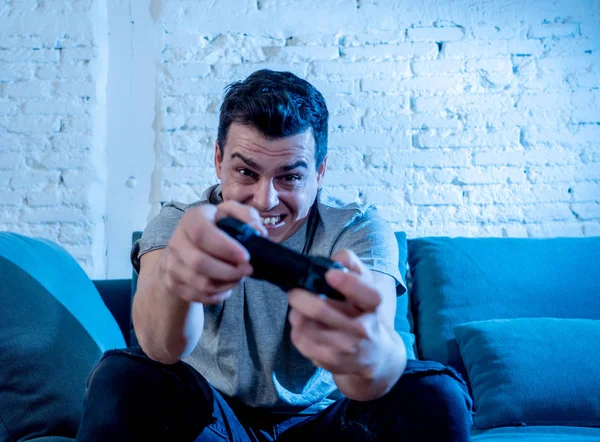 Portrait of young student man spending time playing video games using wireless remote joystick with freak intense happy face having fun in Male game addiction to console play station and video.